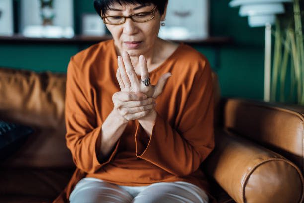 senior elderly asian lady rubbing her arthritic hands